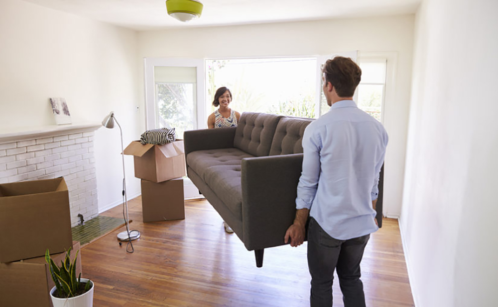 Couple Carrying Sofa Into New Home On Moving Day